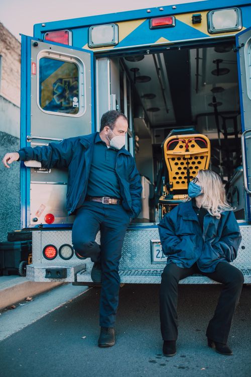 Two paramedics at the back of an ambulance preparing medical equipment