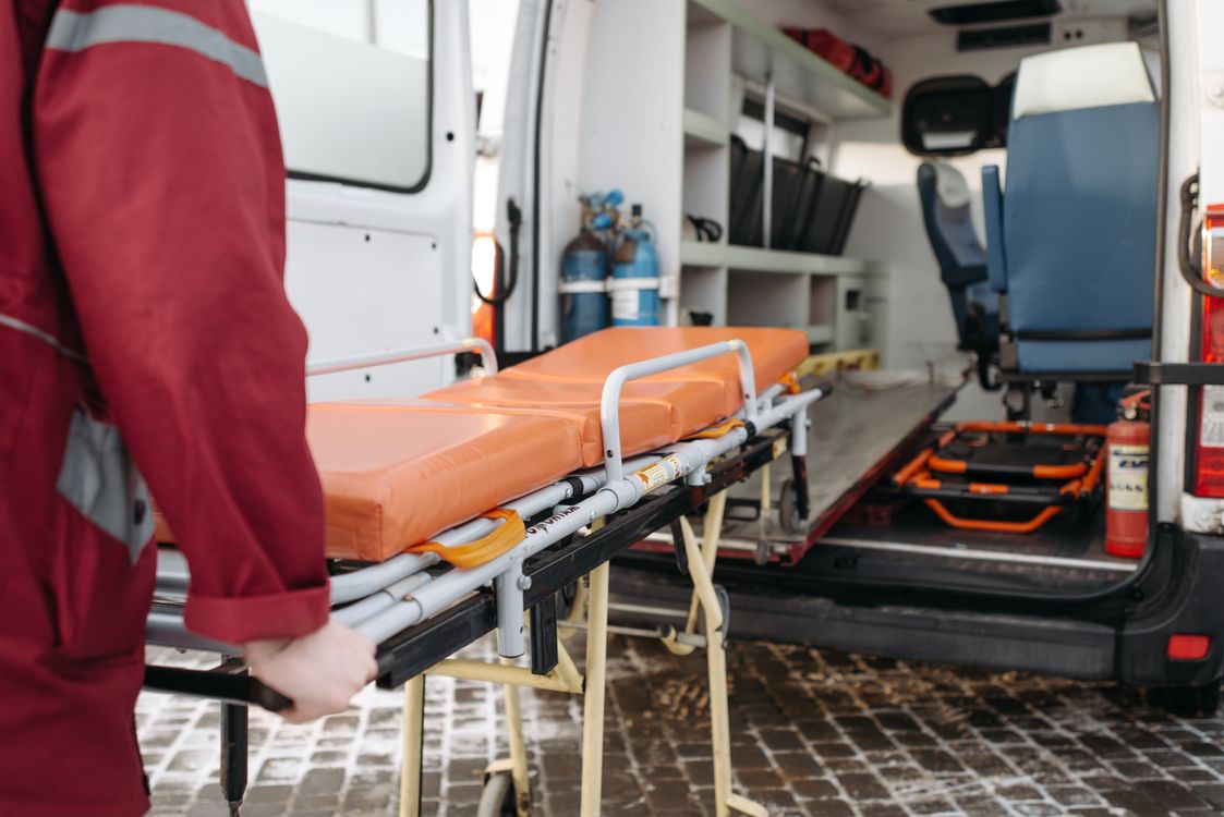 EMT crew moving a patient on a stretcher toward a waiting ambulance